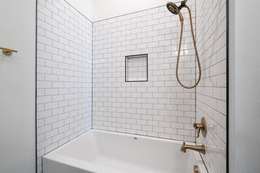 A rectangular bathtub surrounded by white wall tiles