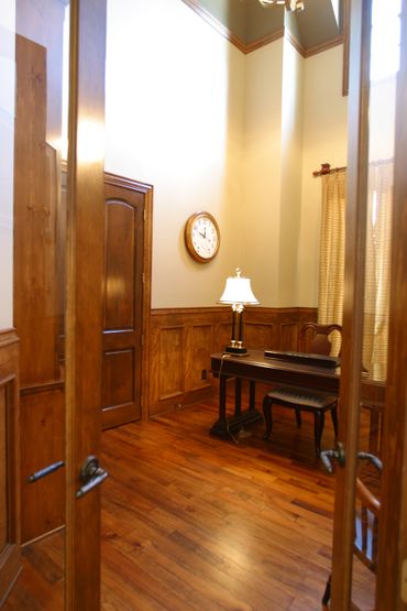 An office with an elegant wooden chair and table, wood wainscoting, and vintage lamp