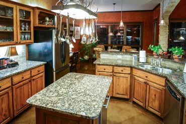 A small kitchen with wooden cupboards and marble countertops