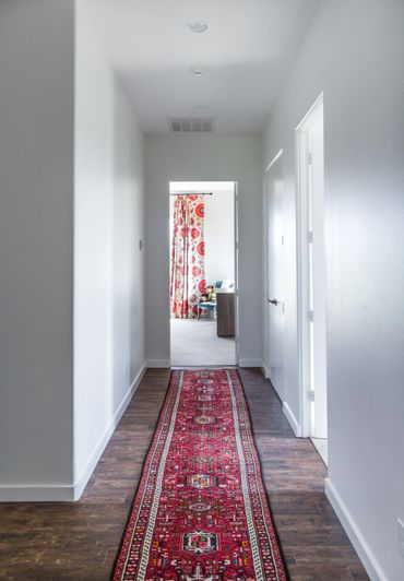 Hallway with wooden floors and a red, patterned carpet