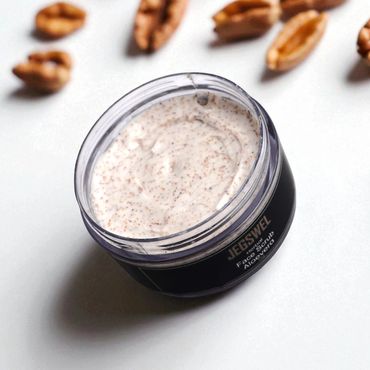 Jar of face scrub with pecans scattered around.