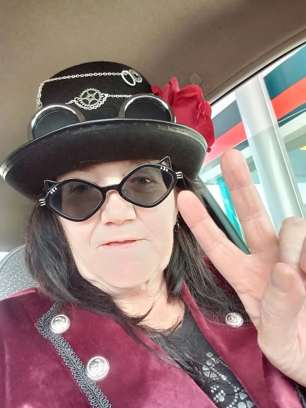 Woman in steampunk-inspired outfit showing peace sign.