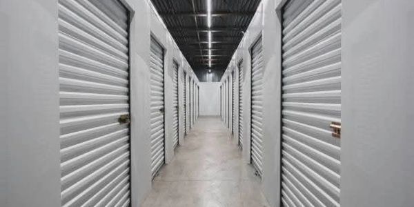 A hallway lined with white storage unit doors in a self-storage facility.