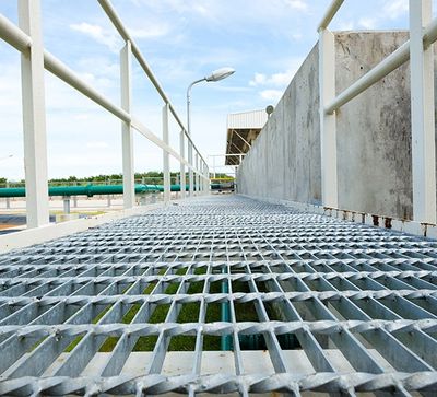 Industrial metal walkway with railings under a blue sky.