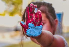 A child with finger-paint on their hand.