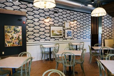 Chic cafe interior with patterned walls and pastel green chairs.