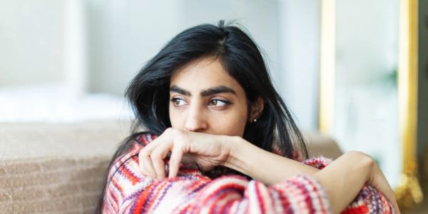 A woman in a colorful sweater looks contemplative.