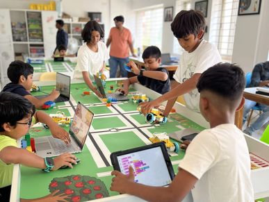 Children engaged in programming and robotics activities in a classroom.