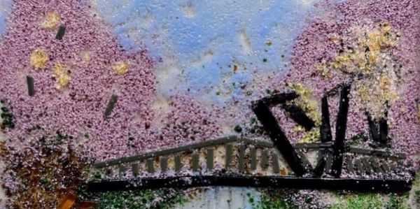 A bridge surrounded by blossoming pink trees under a blue sky.