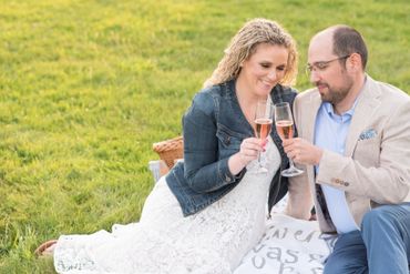 Engaged couple on the grass, cheers to their engagement with champagne. 