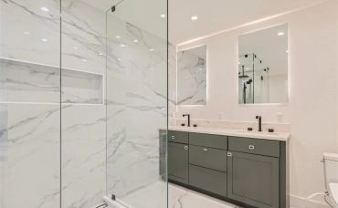 Modern bathroom with marble shower and double vanity.
