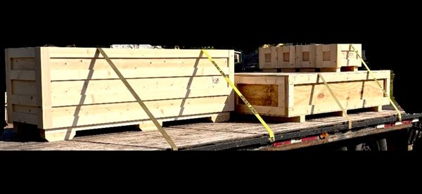 Wooden crates secured with yellow straps on a flatbed truck.