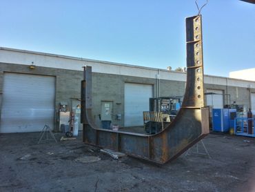 Large metal industrial structure placed outdoors near warehouse doors.