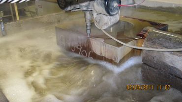 Waterjet cutting machine slicing a thick metal block.