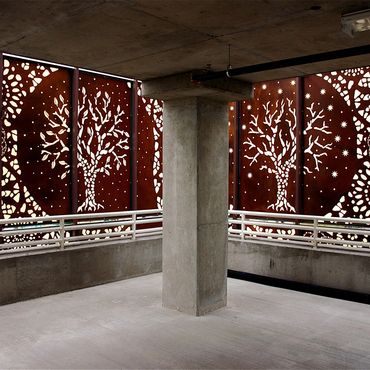Concrete parking garage with decorative tree-patterned metal panels.