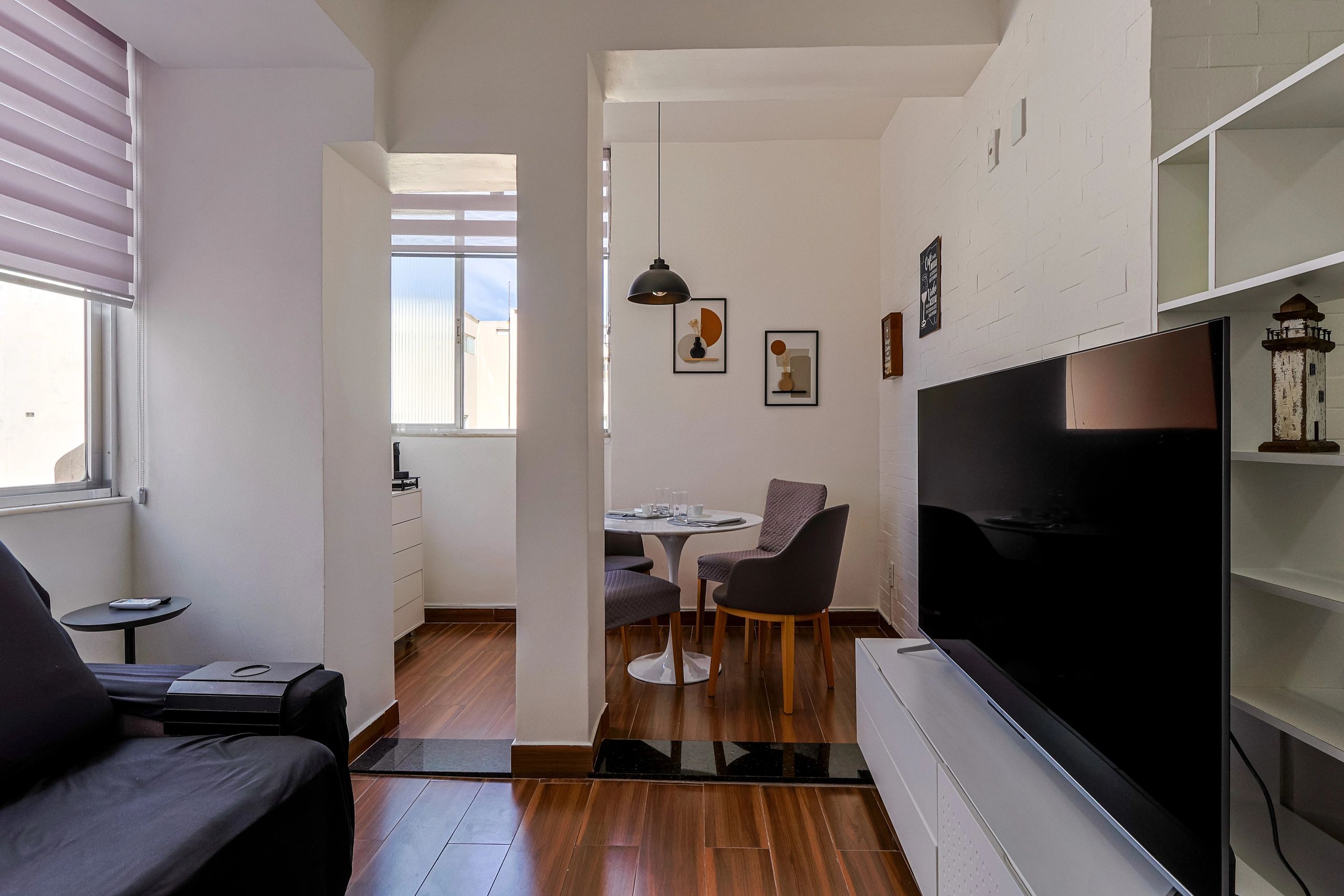 Modern living room with dining area, wooden floors, and minimalist decor.