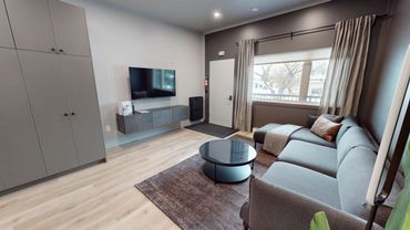 Modern living room with gray sofa and wall-mounted TV.