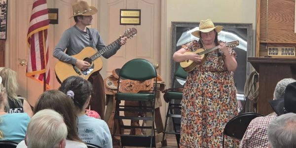 Two musicians in cowboy hats performing for an audience.
