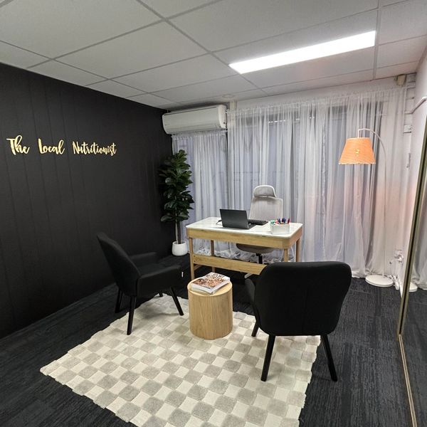 Modern nutritionist office with black chairs and a wooden desk.