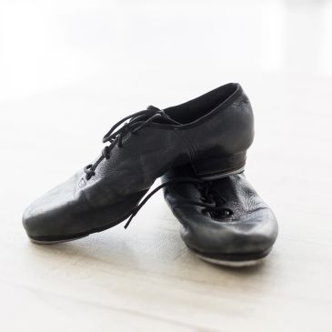 A pair of black leather jazz shoes neatly placed on a light surface.