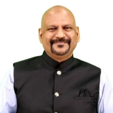 Smiling bald man with a beard in a black vest.