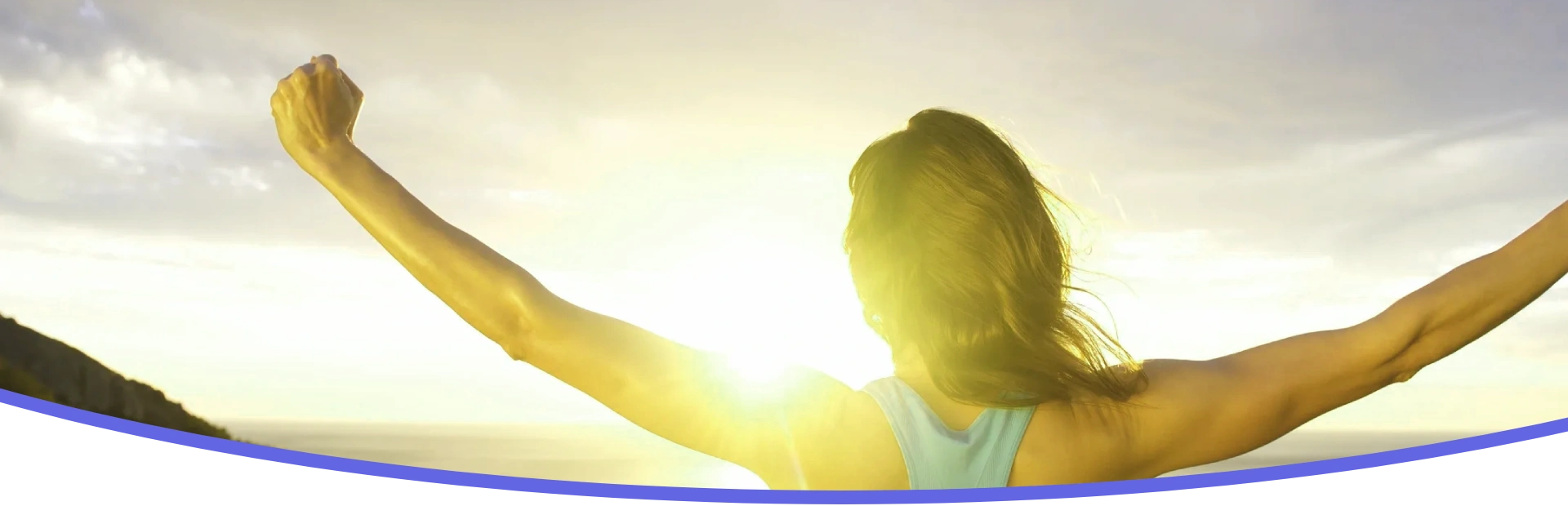 Woman reaching arms up in front of sunshine