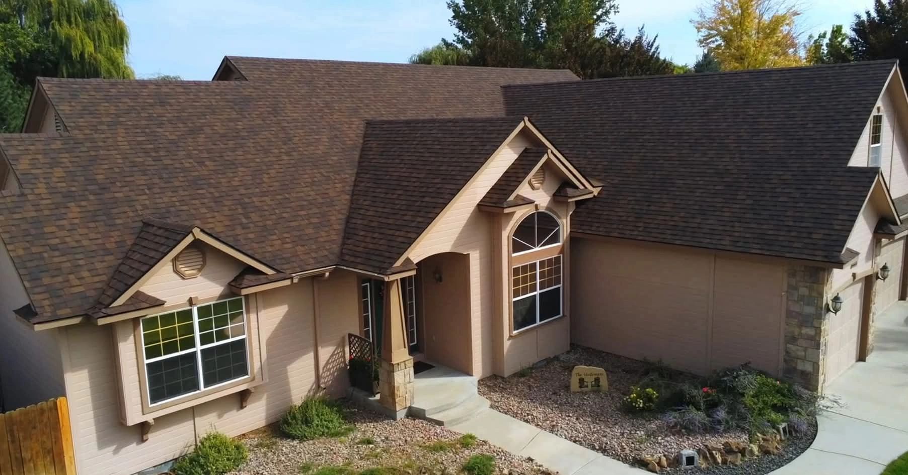 Single-story house with brown roof and beige walls surrounded by a rock garden.