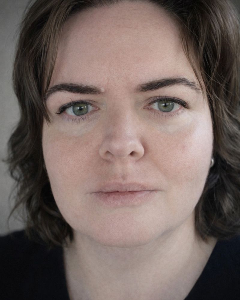 Close-up portrait of a woman with green eyes and short brown hair.