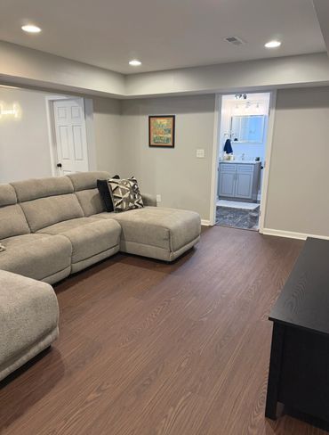 Modern living room with gray sectional sofa and wooden floor.