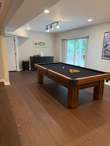 A modern game room with a pool table and large sliding glass door.