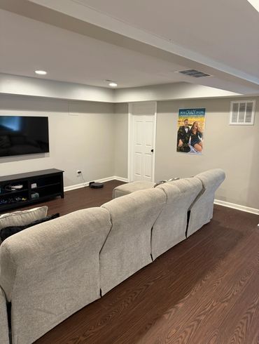 Cozy living room with beige sofa, wooden floor, wall-mounted TV, and a colorful poster.