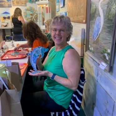 Smiling woman holding a blue craft fan.