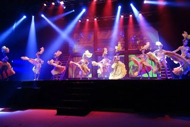 Dancers in colorful costumes performing on a brightly lit stage.