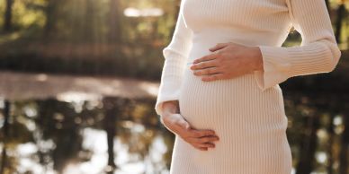 Pregnant woman holding her belly outdoors.