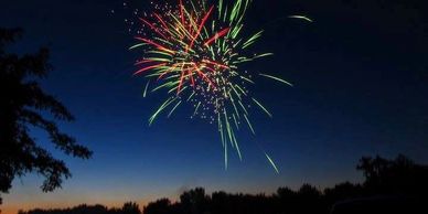 Red and green fireworks exploding on a dark blue night sky