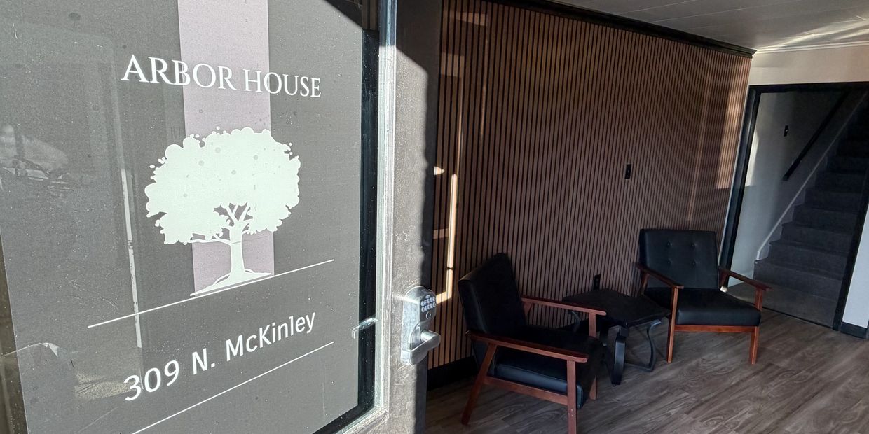 Entrance to Arbor House with modern chairs and staircase inside.