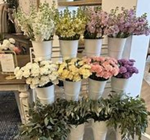 legant floral centerpiece featuring roses, lilies, and stock in a white vase.