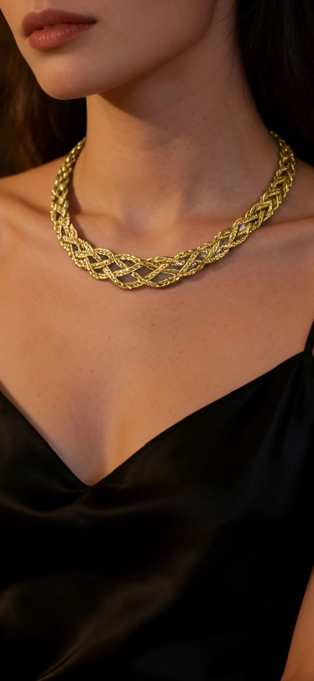 Woman wearing a gold braided necklace and black top.