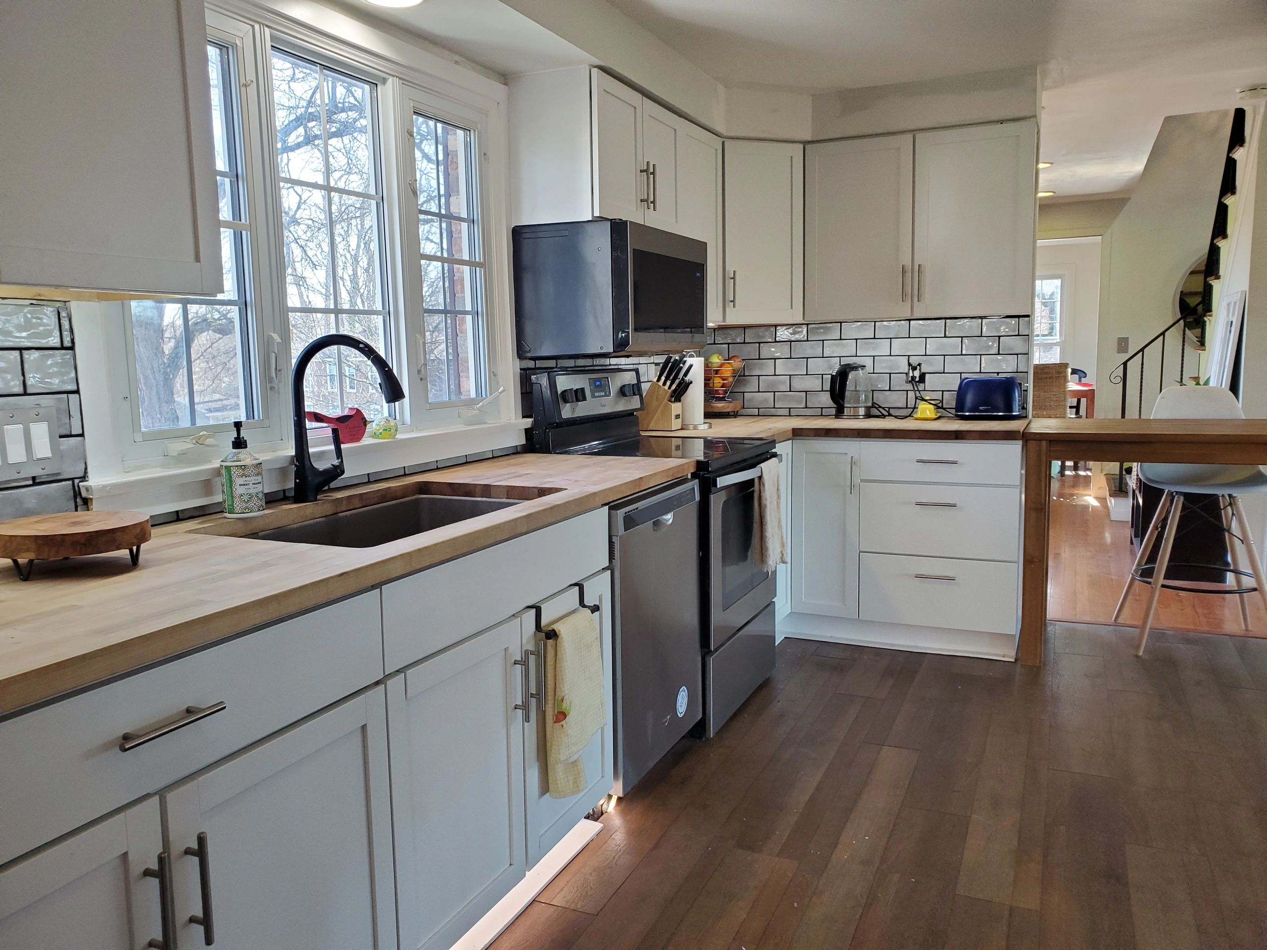 Modern kitchen with white cabinets and wooden countertops.