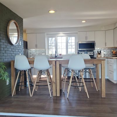 Modern kitchen with a wooden table and white chairs under ceiling lights.