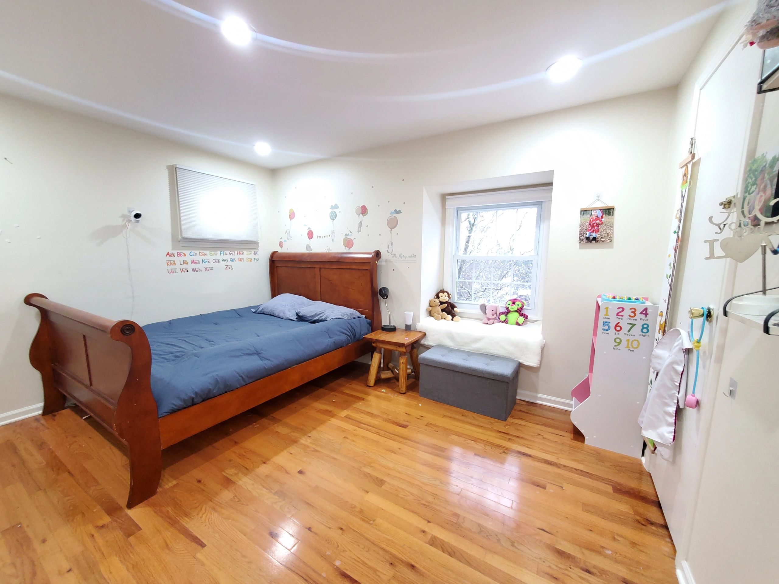 Cozy bedroom with wooden bed, toys, and bright lighting.