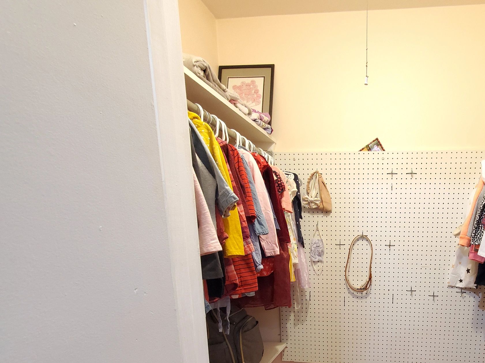 Organized walk-in closet with hanging clothes and shelves.