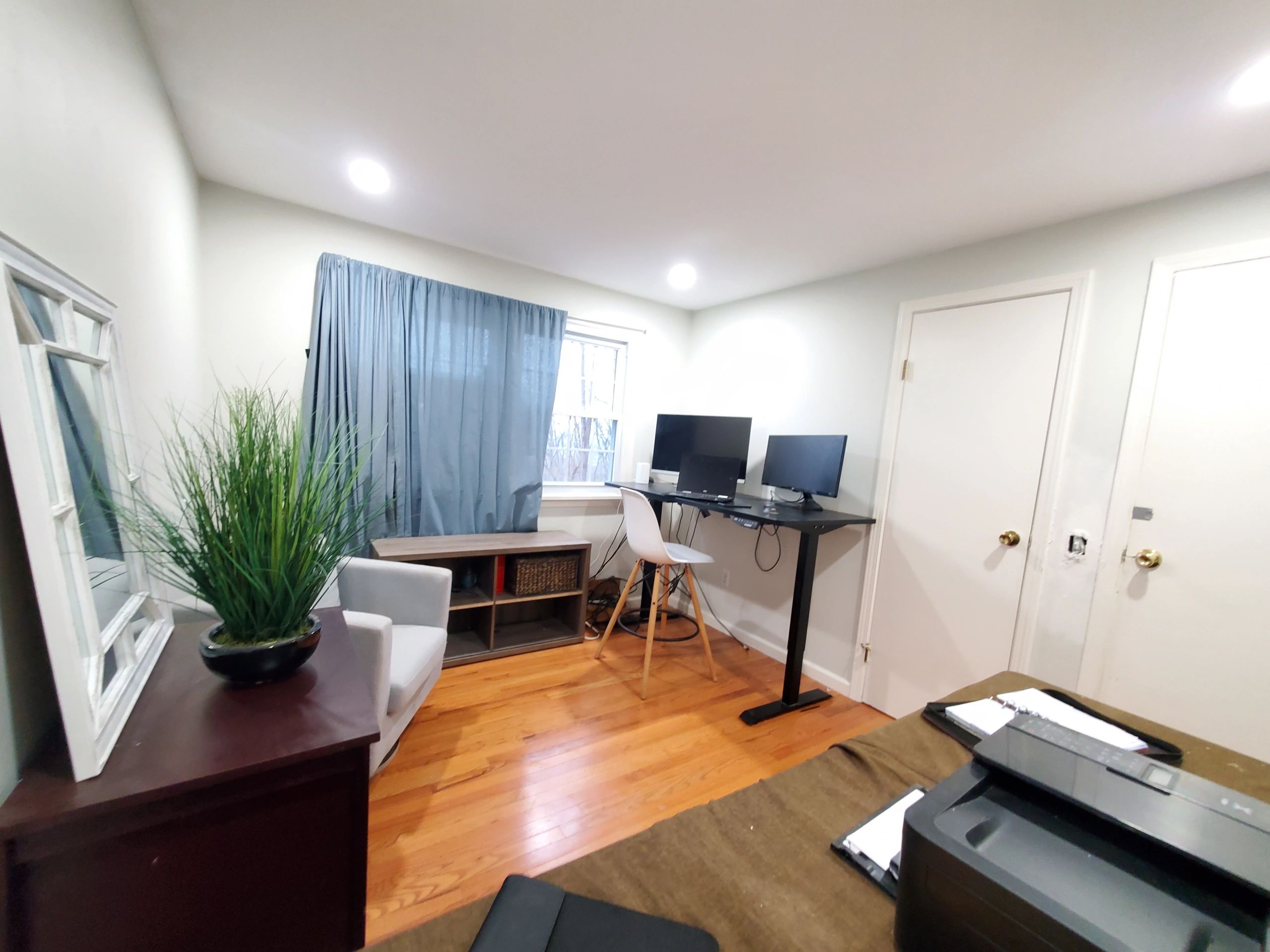 Bright home office with wooden floors, dual monitors, and cozy decor.