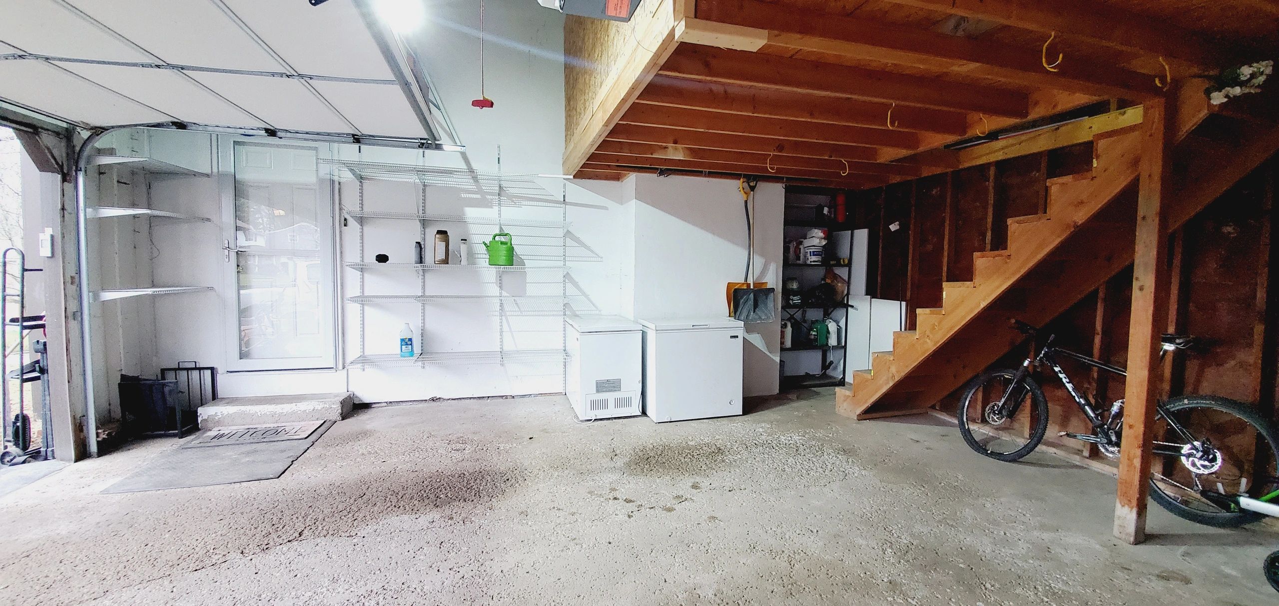 Clean and organized garage with wooden stairs, shelves, and a bicycle.