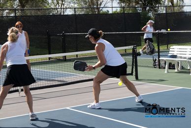 Women playing pickleball outdoors on a sunny day.
