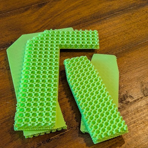Green 3D-printed objects with honeycomb structure on a wooden surface.