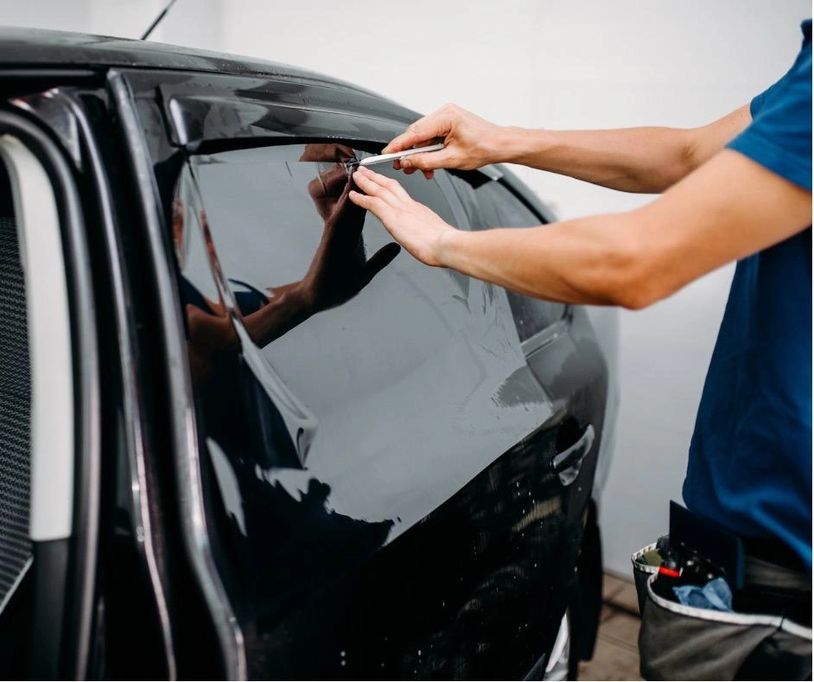 Installer precisely cutting tint to apply on a vehicle.