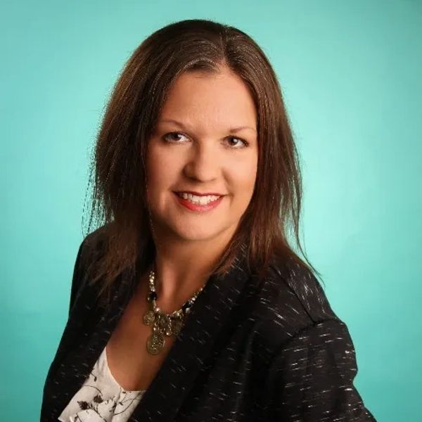 Professional woman smiling confidently against a teal background.