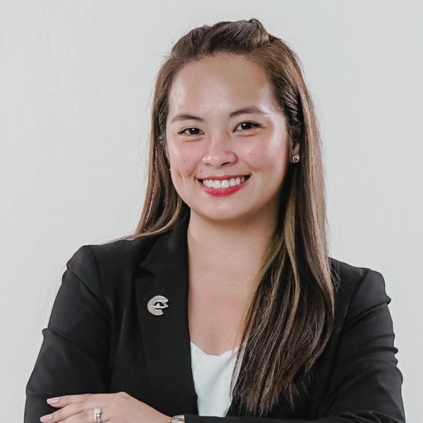Confident woman in professional black blazer smiling with arms crossed.