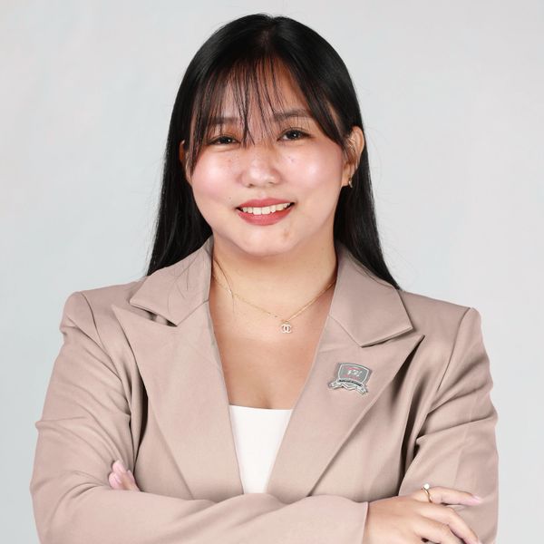 Confident woman in beige blazer smiling with folded arms.